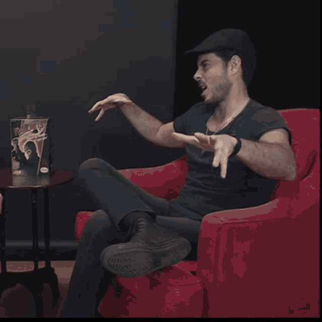 a man sitting in a red chair with a magazine on a table that says ' a man 's life '