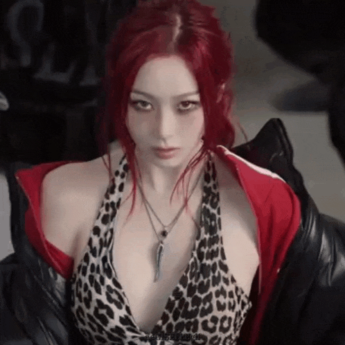 a woman with red hair and a leopard print top is wearing a red jacket and a necklace .