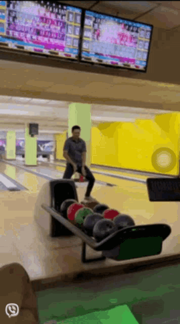 a man is playing bowling in a bowling alley with a phone icon