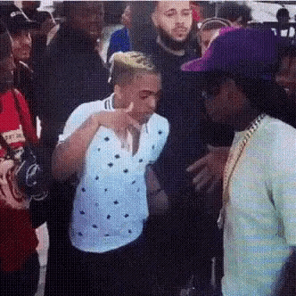 a man in a purple hat is talking to another man in a white shirt