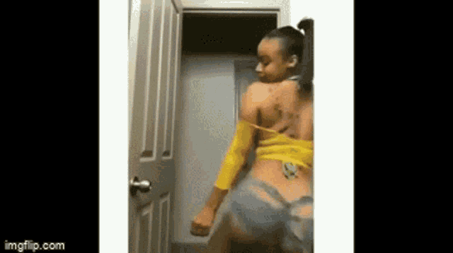 a woman in a yellow shirt and blue shorts is dancing in a room .