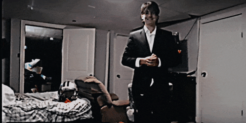 a man in a suit is standing in a bedroom