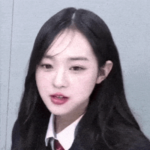 a close up of a young woman wearing a school uniform and tie .