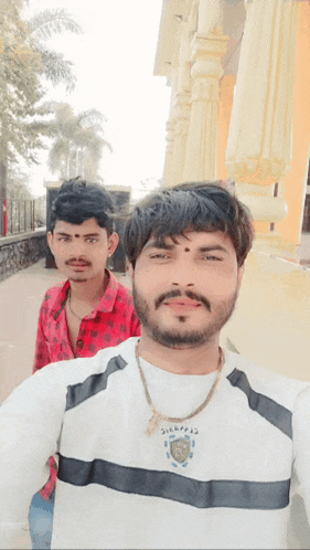 two men are posing for a picture with one wearing a shirt that says ' singhraj '