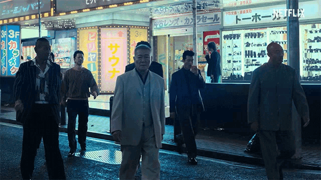 a group of men are walking down a street in front of a store that says 3f