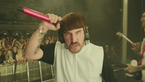 a man wearing headphones holds a pink object in his hand