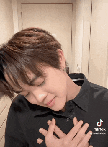 a tiktok video of a young man with his hands on his heart