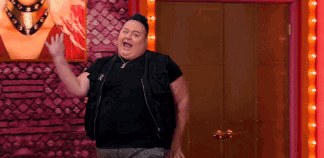 a man in a black vest is waving his hand