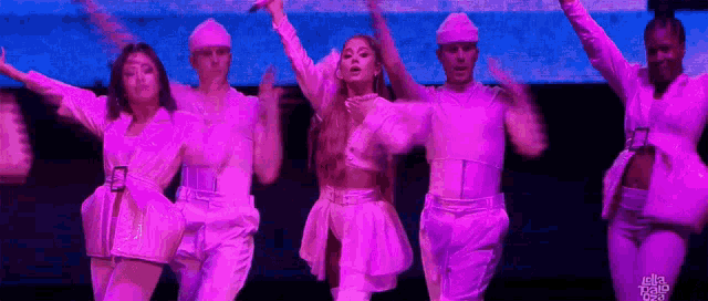 ariana grande is performing on stage with a group of dancers in pink .