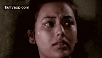 a close up of a woman 's face with a tear running down her cheek .