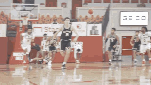 a basketball game is underway with a geico sign in the background