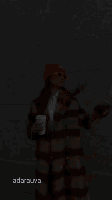 a woman wearing an orange hat and sunglasses is holding a starbucks coffee cup