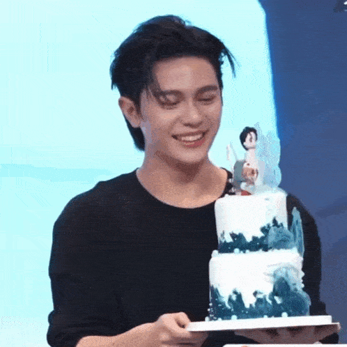 a man is holding a birthday cake with a figurine on top .