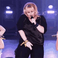 a woman singing into a microphone while dancing on a stage