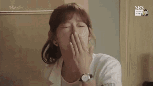 a woman is yawning with her hand over her mouth .