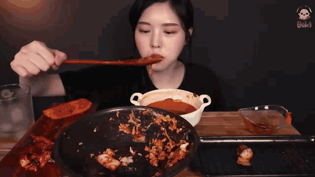 a woman eating a bowl of food with chopsticks and a skull on the screen