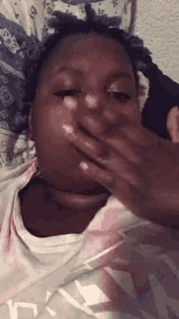 a woman is laying in bed covering her mouth with her hand .