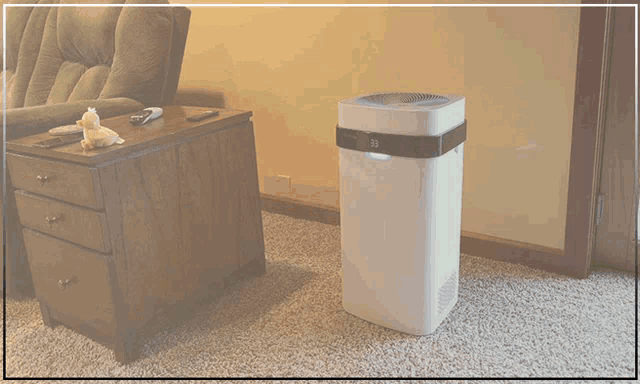 an air purifier is sitting on the floor next to a chair