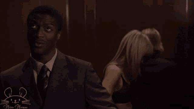 a man in a suit and tie stands in an elevator with a pink mouse on the bottom