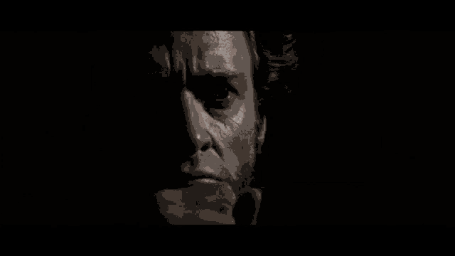 a close up of a man 's face with a beard in the dark .