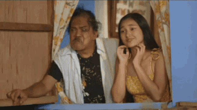 a man and a woman are standing next to each other in a room .