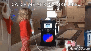 a little girl is singing into a microphone while playing a karaoke machine .