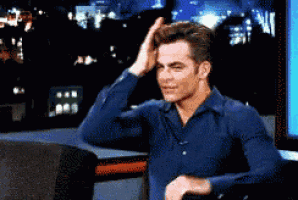 a man in a blue shirt is touching his head