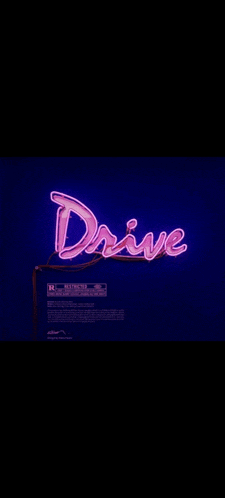 a neon sign that says `` drive '' is lit up in a dark room .