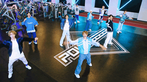 a group of young men are dancing in a gym with a logo that says 20 on the floor