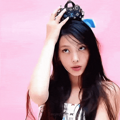 a woman with long black hair is holding a small louis vuitton bag on her head