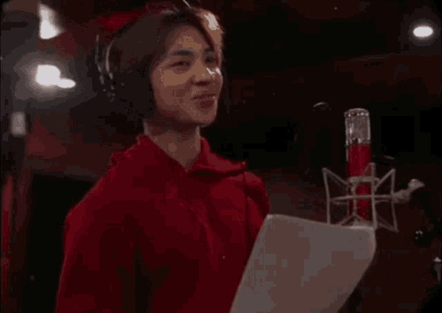a young man wearing headphones is singing into a microphone in a studio .