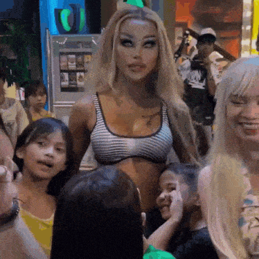 a woman in a striped bra stands in front of a crowd of people