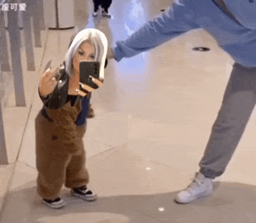a woman is taking a picture of herself in a mirror while a small child is standing next to her .