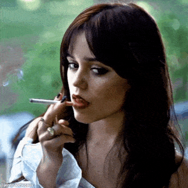 a close up of a woman smoking a cigarette with a ring on her finger