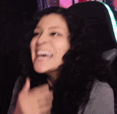 a woman with curly hair is sitting in a chair and laughing .