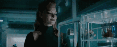 a woman in a black turtleneck stands in front of a refrigerator .