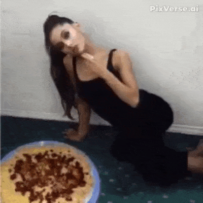 a woman is kneeling on the floor in front of a pizza .