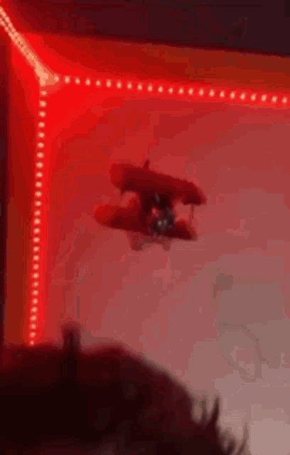 a toy airplane is flying through a red light .