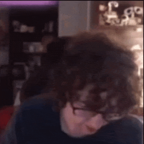 a man with curly hair is making a funny face in front of a computer screen .