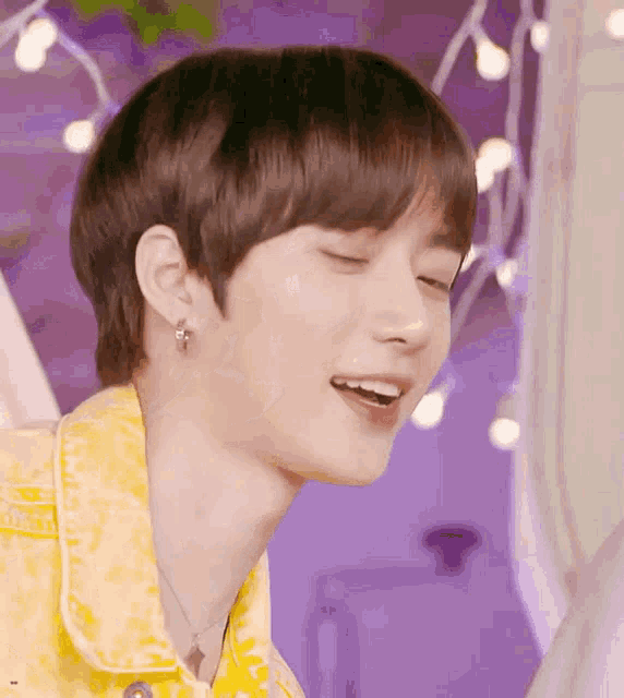 a close up of a person 's face with their eyes closed and wearing a yellow shirt .