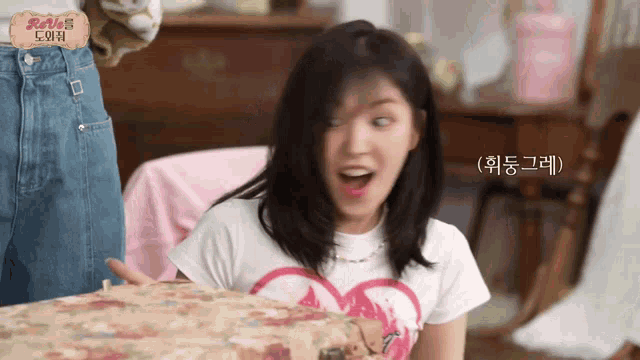 a woman is sitting at a table with a suitcase in front of her and making a funny face .