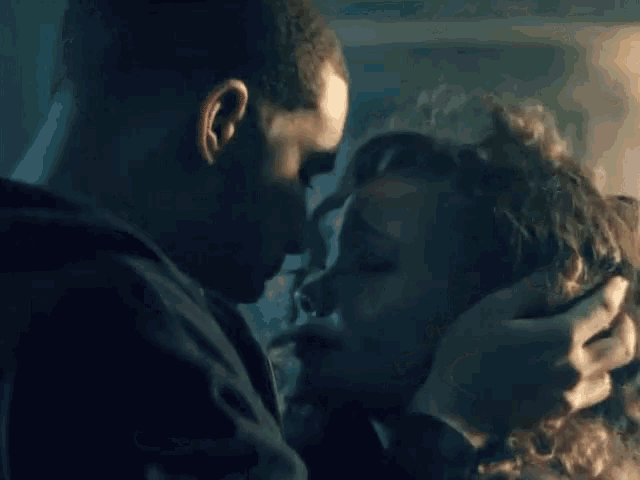 a man and a woman are kissing in a dark room in a dark room .