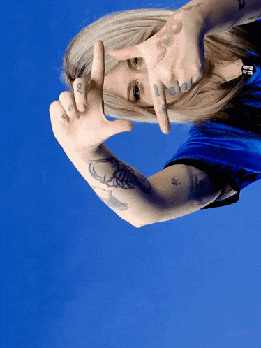 a woman with a tattoo on her arm is making a frame with her fingers