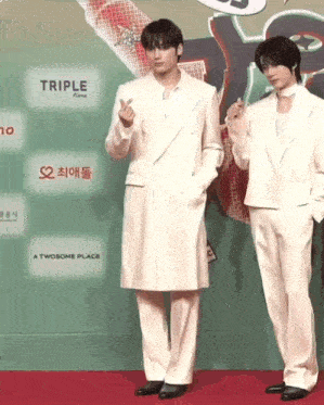 two men are standing next to each other on a red carpet .