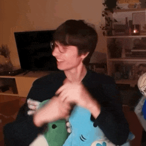 a man is holding a stuffed animal in a living room while wearing glasses .