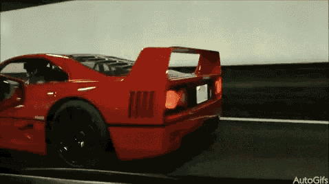 a red sports car is driving down a road with the words autogifs on the bottom