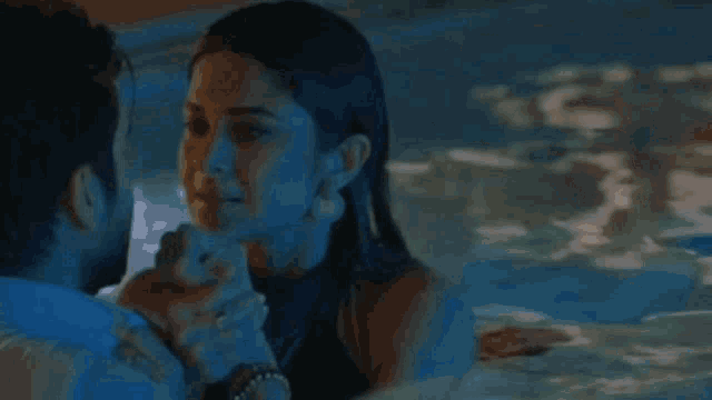 a man and a woman are dancing in a pool at night .