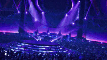 a crowd of people are watching a performance on a stage with a blue light coming out of it