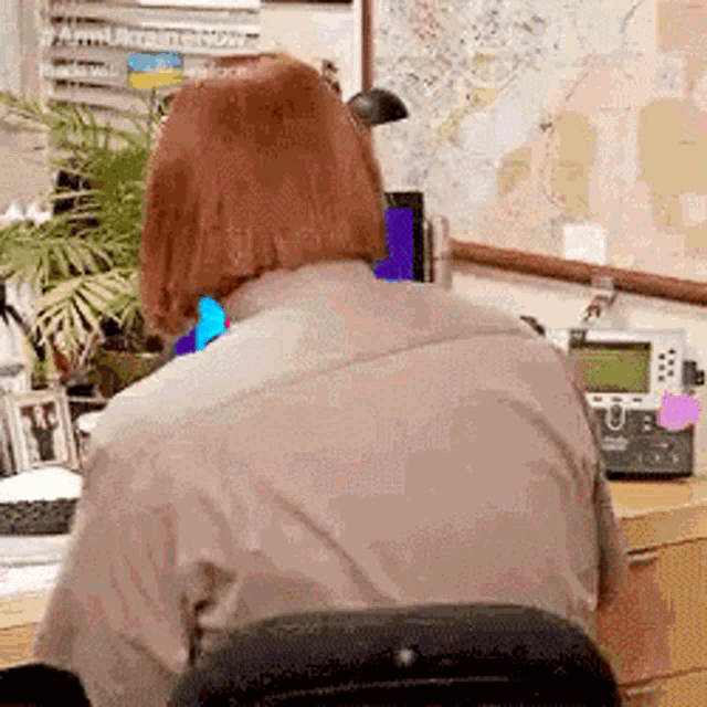 a woman is sitting at a desk in front of a map and a phone .