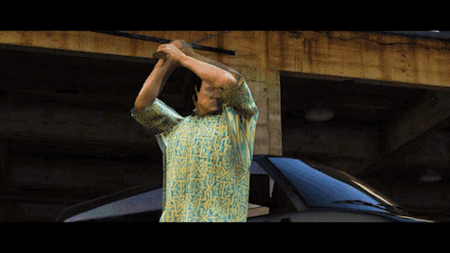 a man in a hawaiian shirt is standing in front of a black car